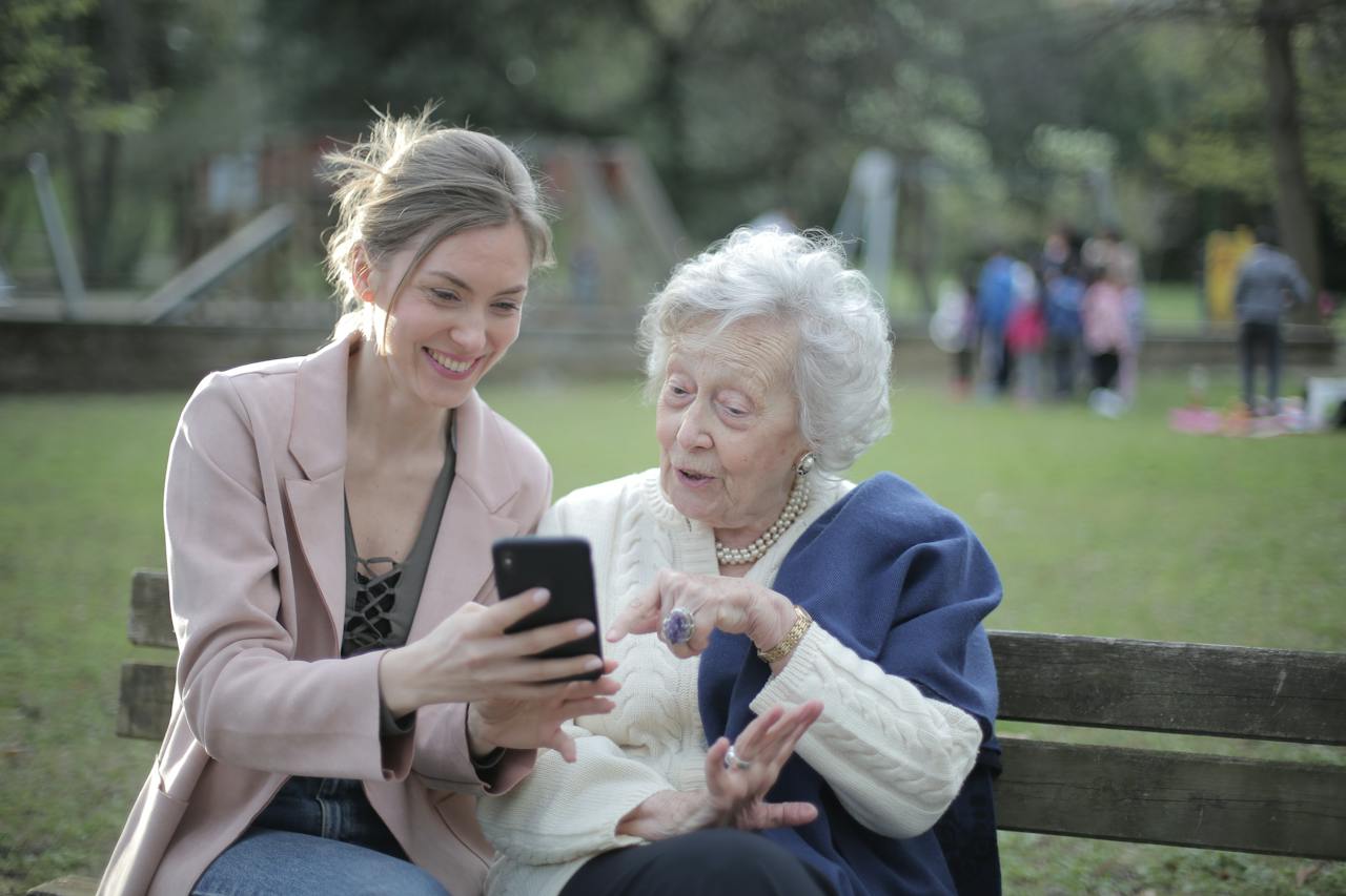 A young woman and an elderly woman looking into a mobile phone with smiles