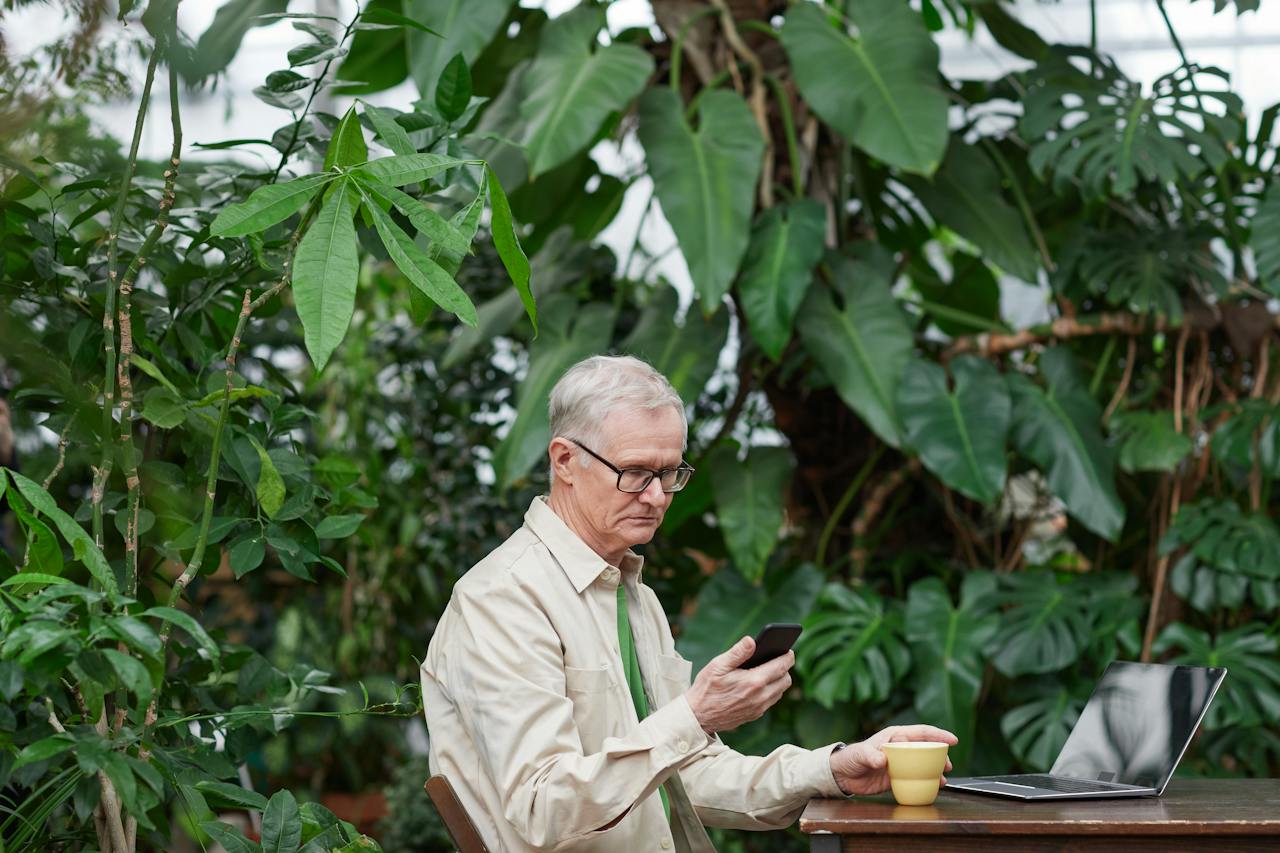 An elderly man sitting and looking into a mobile phone
